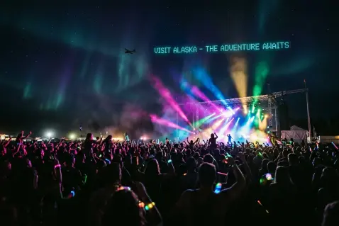 A glowing aerial message above a festival crowd and stage lights